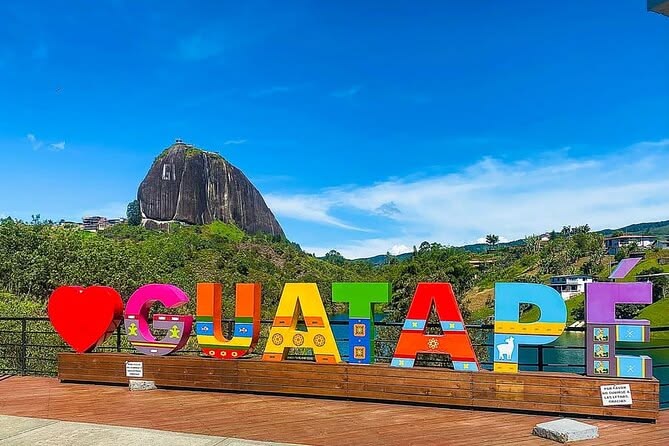 Colorful Guatapé sign with El Peñol Rock in the background